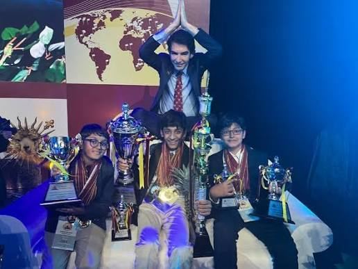 Vihaan on stage at a World Scholar's Cup closing ceremony alongside other scholars holding trophies