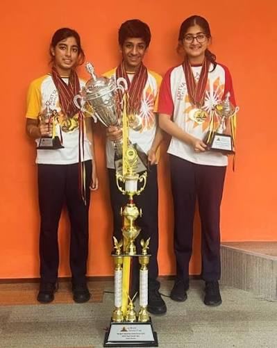Three scholars in school uniform holding a large trophy and medals after the Global Round